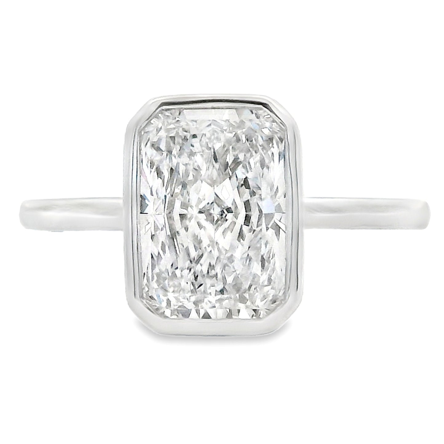 An emerald-cut diamond ring in a silver-toned metal setting with a slim band, shown against a plain white background.