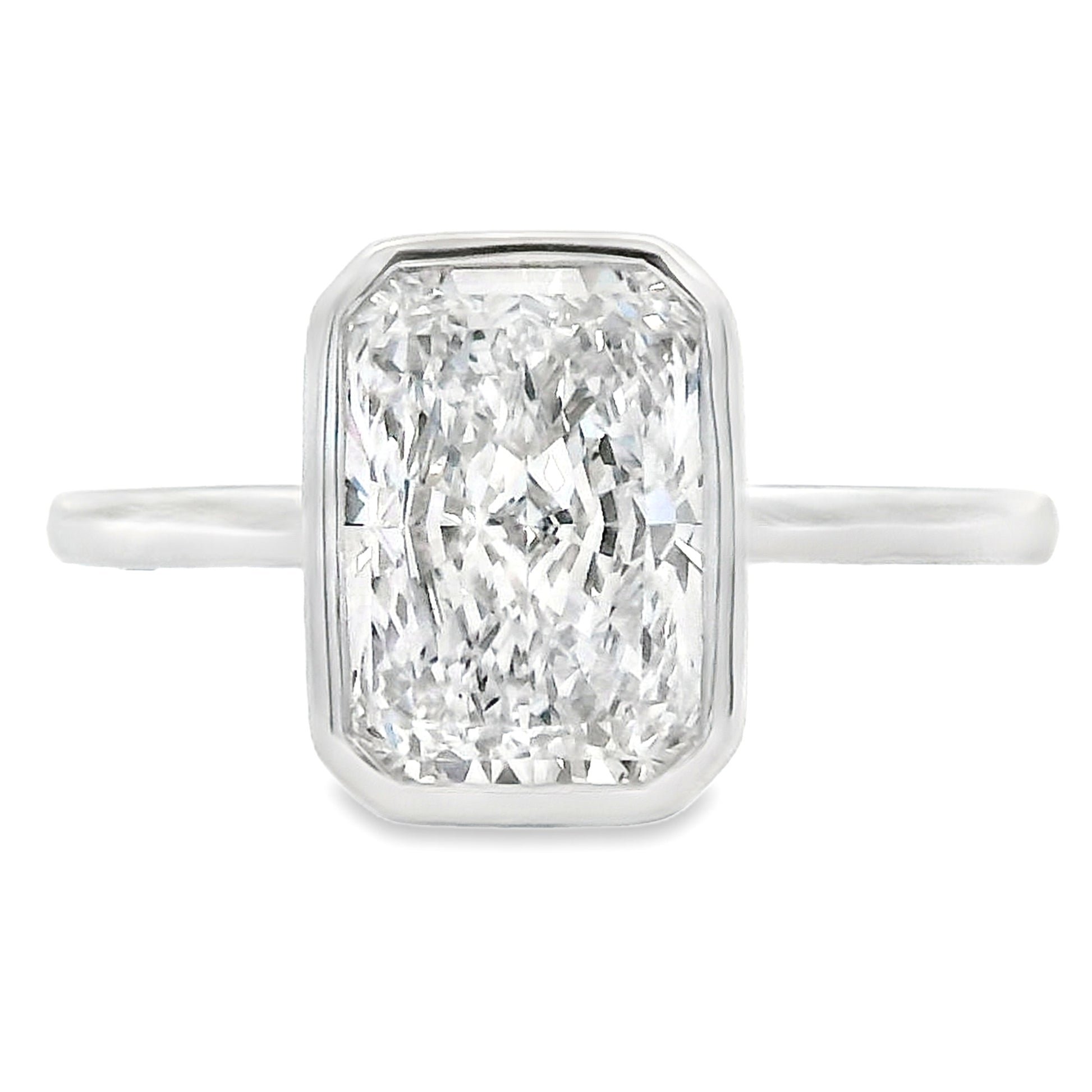 An emerald-cut diamond ring in a silver-toned metal setting with a slim band, shown against a plain white background.