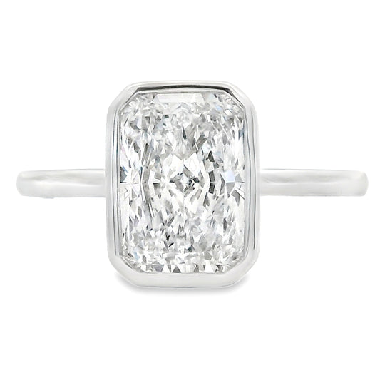 An emerald-cut diamond ring in a silver-toned metal setting with a slim band, shown against a plain white background.