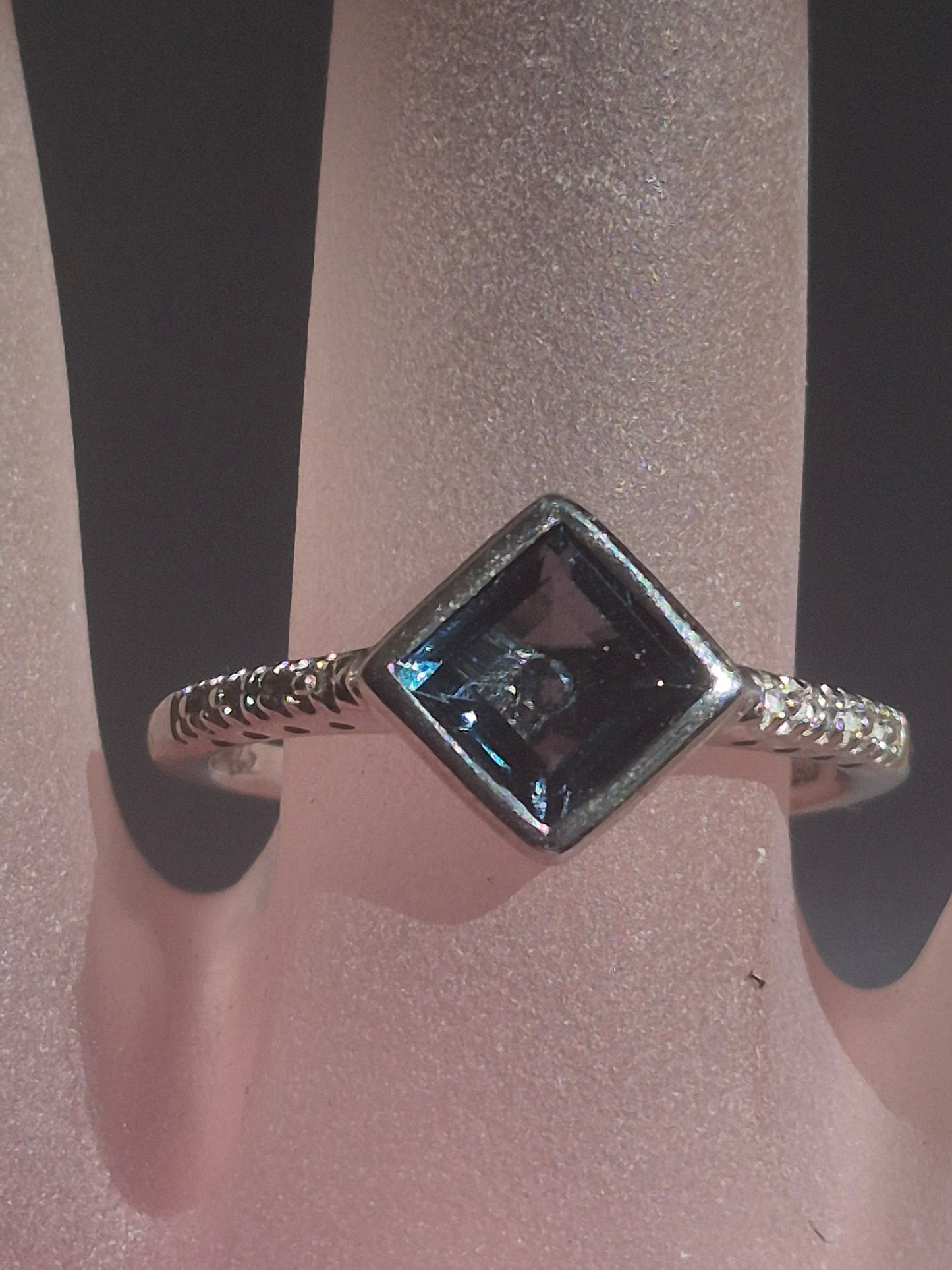 Close-up angled view of the square London Blue Topaz ring in sterling silver, showing the bezel setting and diamond-accented shoulders.