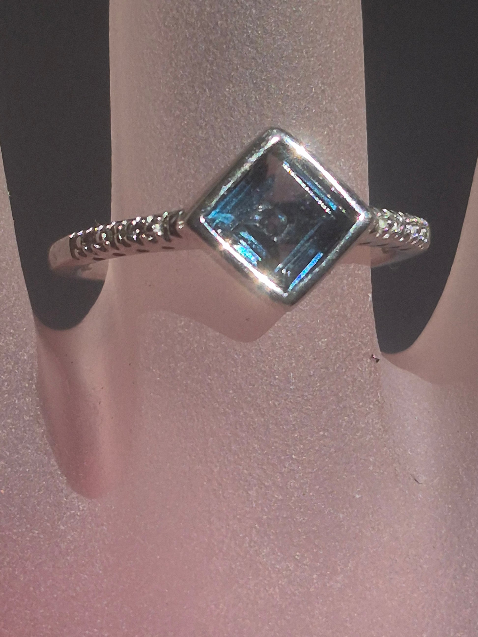 Square London Blue Topaz and diamond ring in sterling silver, shown on a ring display card, diagonal bezel setting with pavé diamond accents on the band.