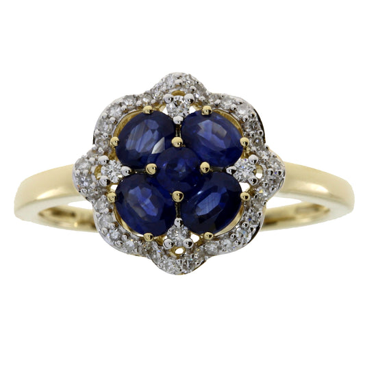 A yellow gold ring featuring a flower-shaped cluster with five oval deep blue sapphires surrounded by a halo of small clear pavé stones, set against a plain white background.